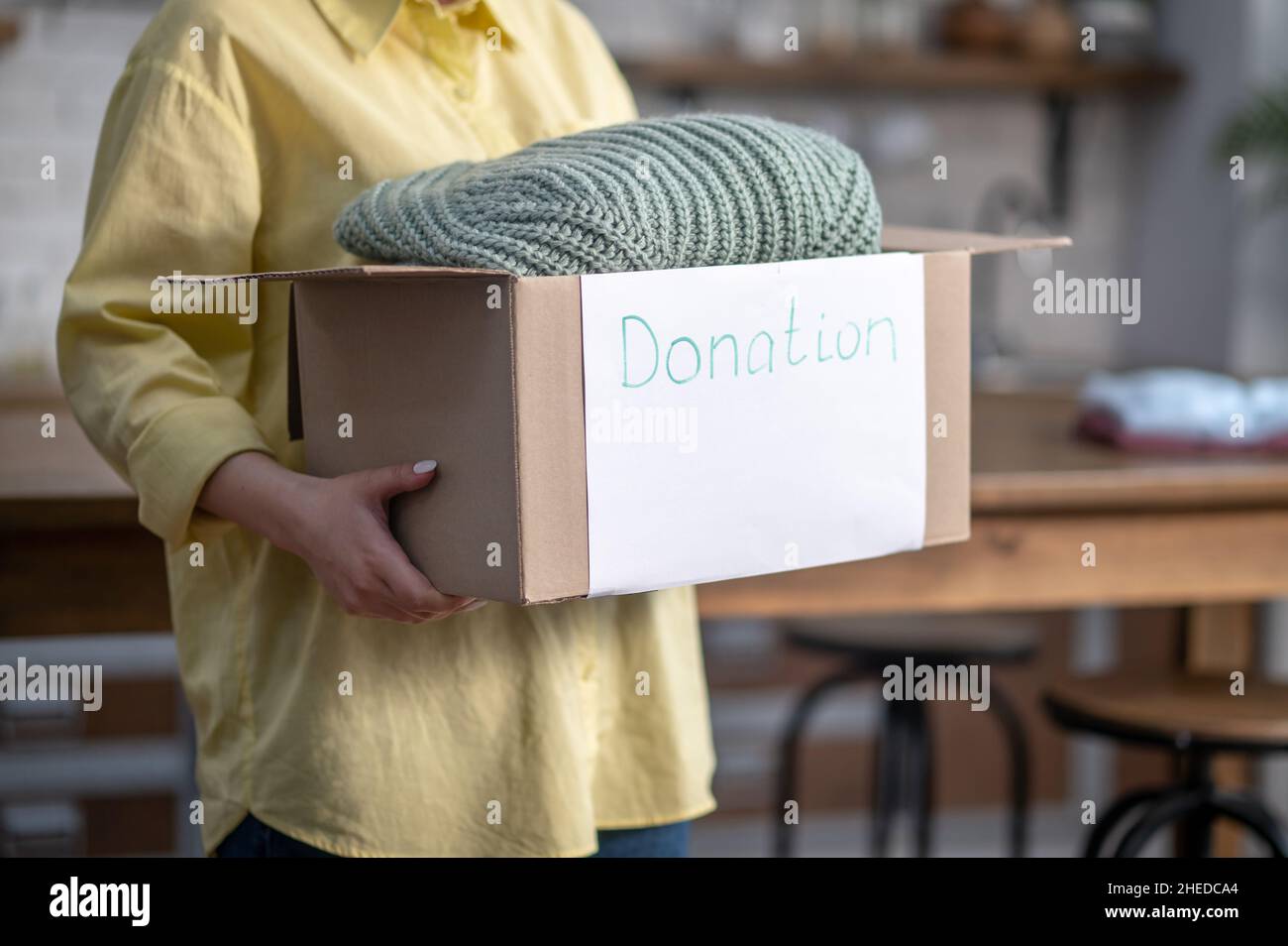 Caucasian lady showing a cardboard box with folded clothes Stock Photo