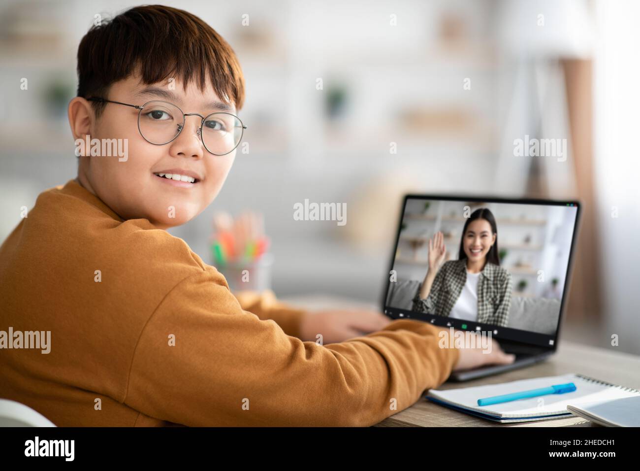 Cheerful asian chubby boy having online class with teacher Stock Photo