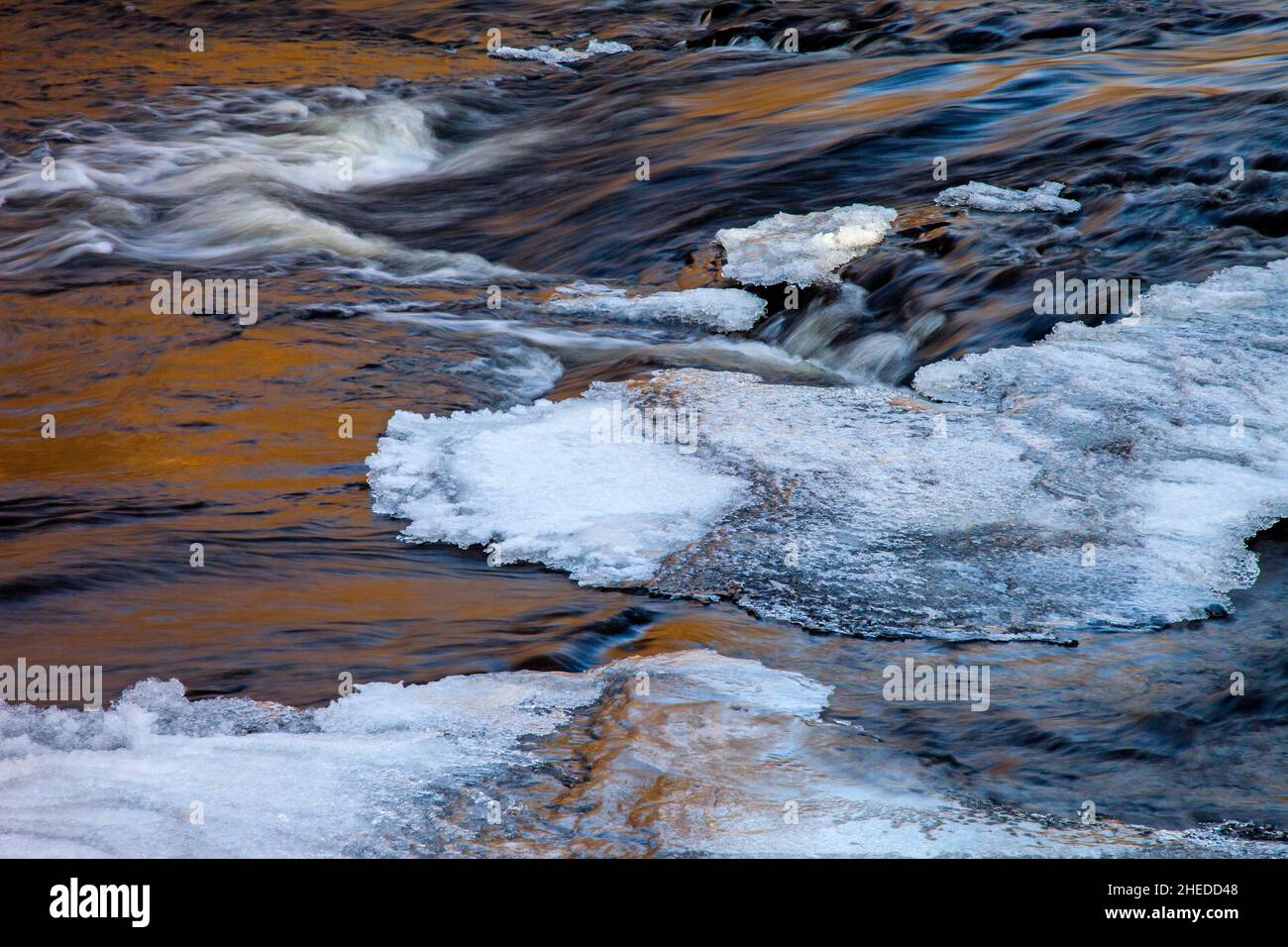 Ice and late afternoon reflections on Tobyhanna Creek in Pennsylvania's Pocono Mountains in early winter. Stock Photo