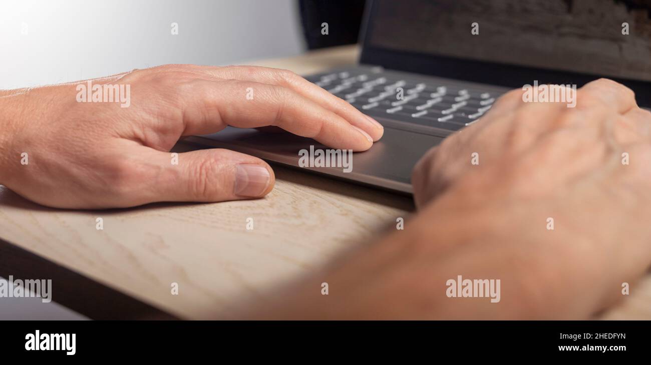 Hand on laptop touchpad, tapping and scrolling with fingers close up. Stock Photo