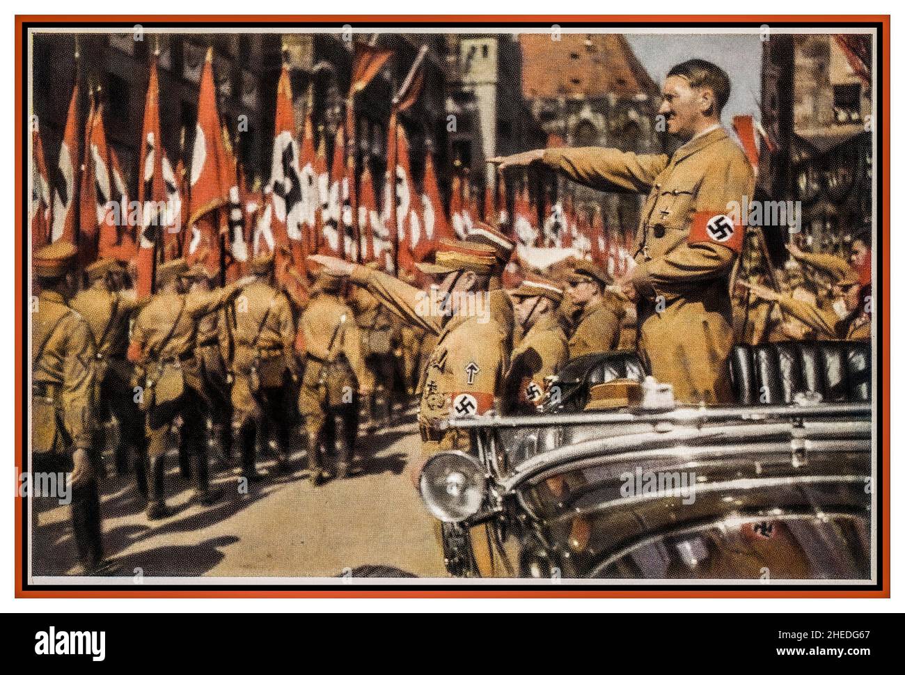Sturmabteilung Adolf Hitler saluting SA Troops Vintage Nazi Germany c1935. Nuremberg Rally, color photo card of Adolf Hitler wearing a swastika armband in open top Mercedes and SA troops marching past with swastika flags, Verlag H. Wiedemann ,Sturmabteilung The official uniform of the SA was the brown shirt with a brown tie  'The Brown Shirts'. Stock Photo