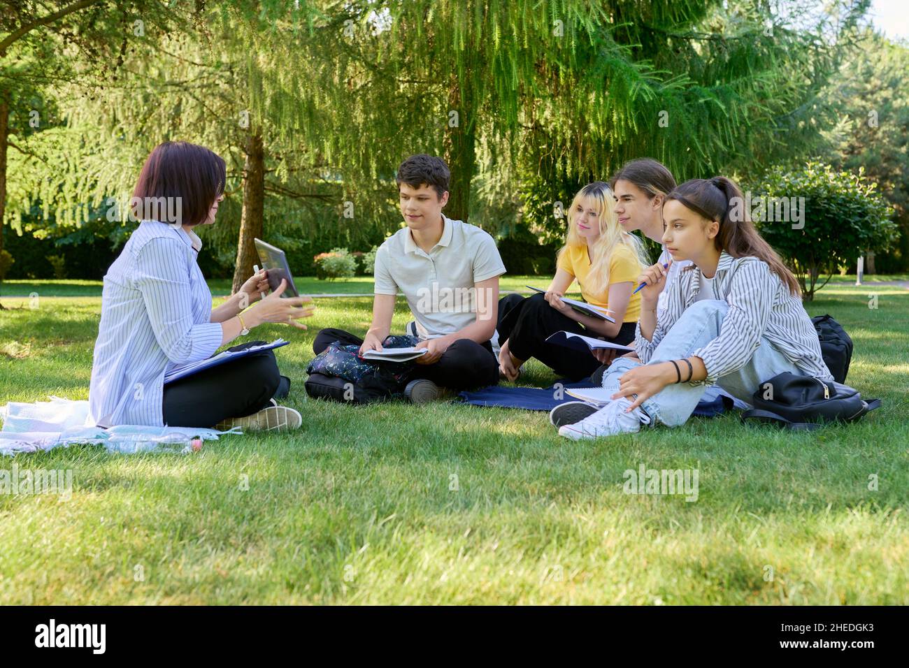 Outdoor, group of students with female teacher sitting on grass Stock ...