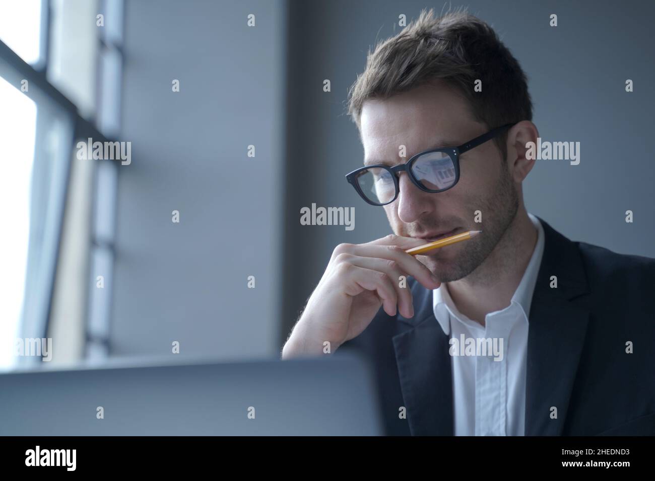 Serious german man executive dressed in formal clothes looking at laptop screen browsing internet Stock Photo