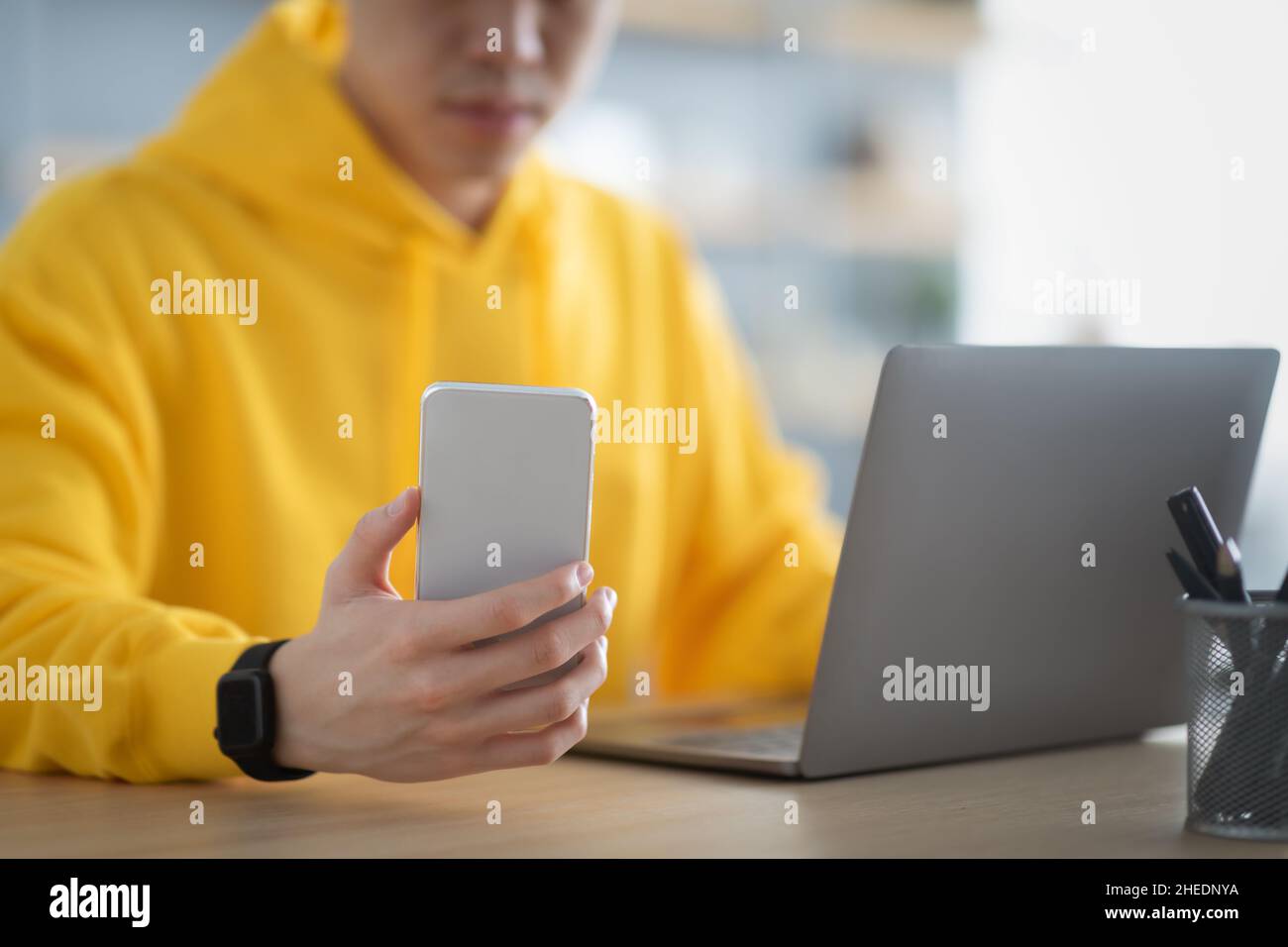 Asian man sitting at desk using cell phone Stock Photo