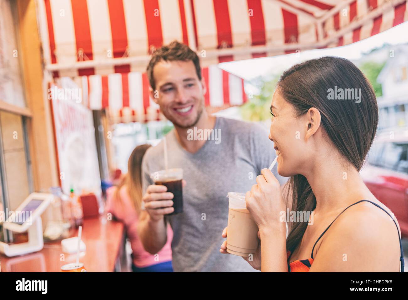 Miami cafe happy couple drinking cold coffee drinks at outdoor terrace of typical retro Florida restaurant. local food. Summer travel tourists Stock Photo