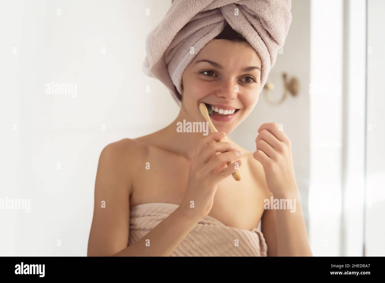 Woman brushes her teeth near the mirror. Stock Photo