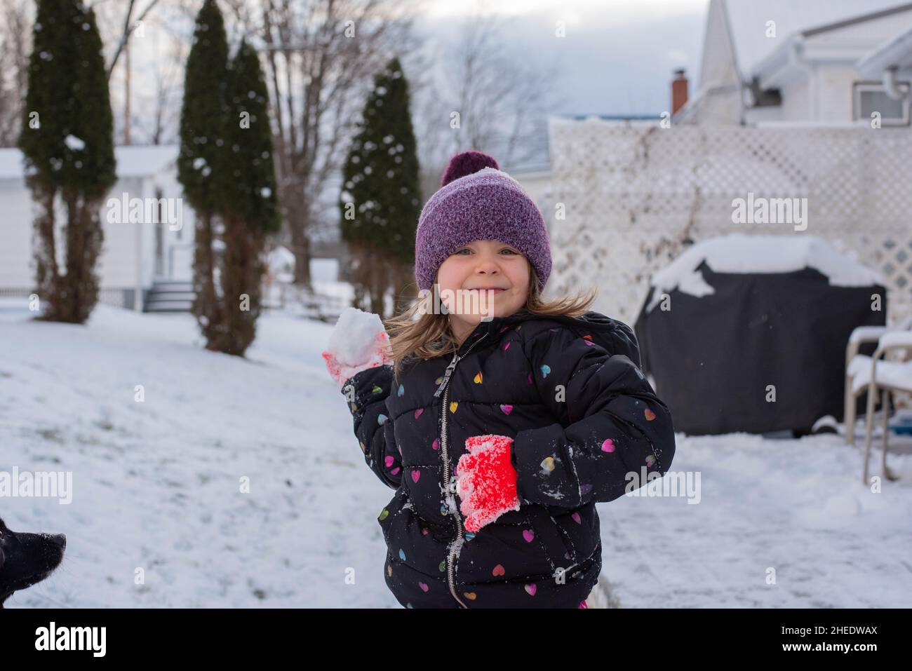 A young child throws a snowball toward the camera during winter. Stock Photo