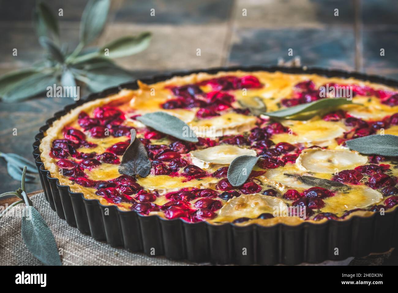 Cranberry goat cheese tart with sage on rustic blue background Stock Photo