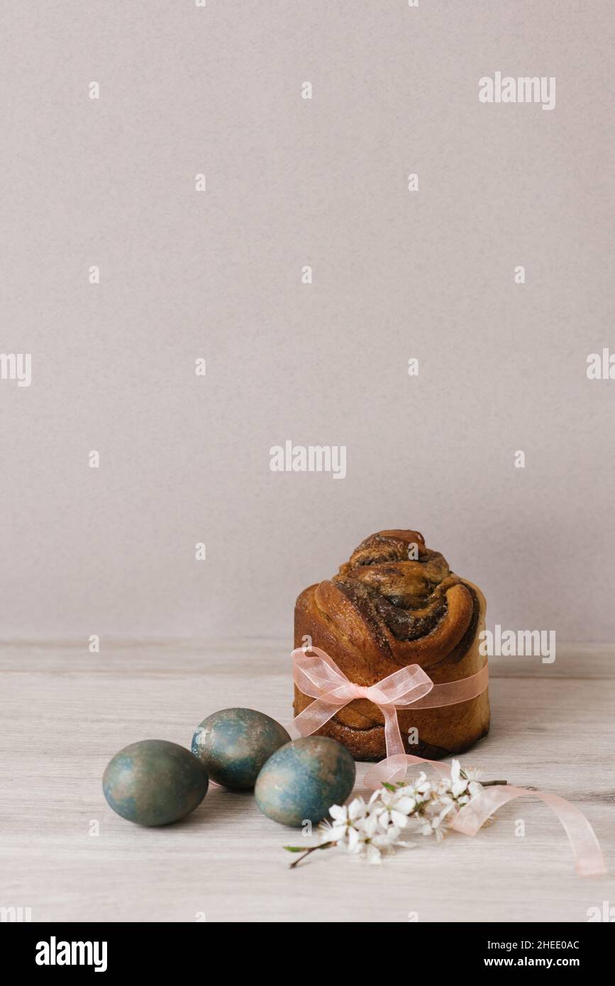 Blooming apple tree branch and Easter cake, painted with eggs on the table Stock Photo