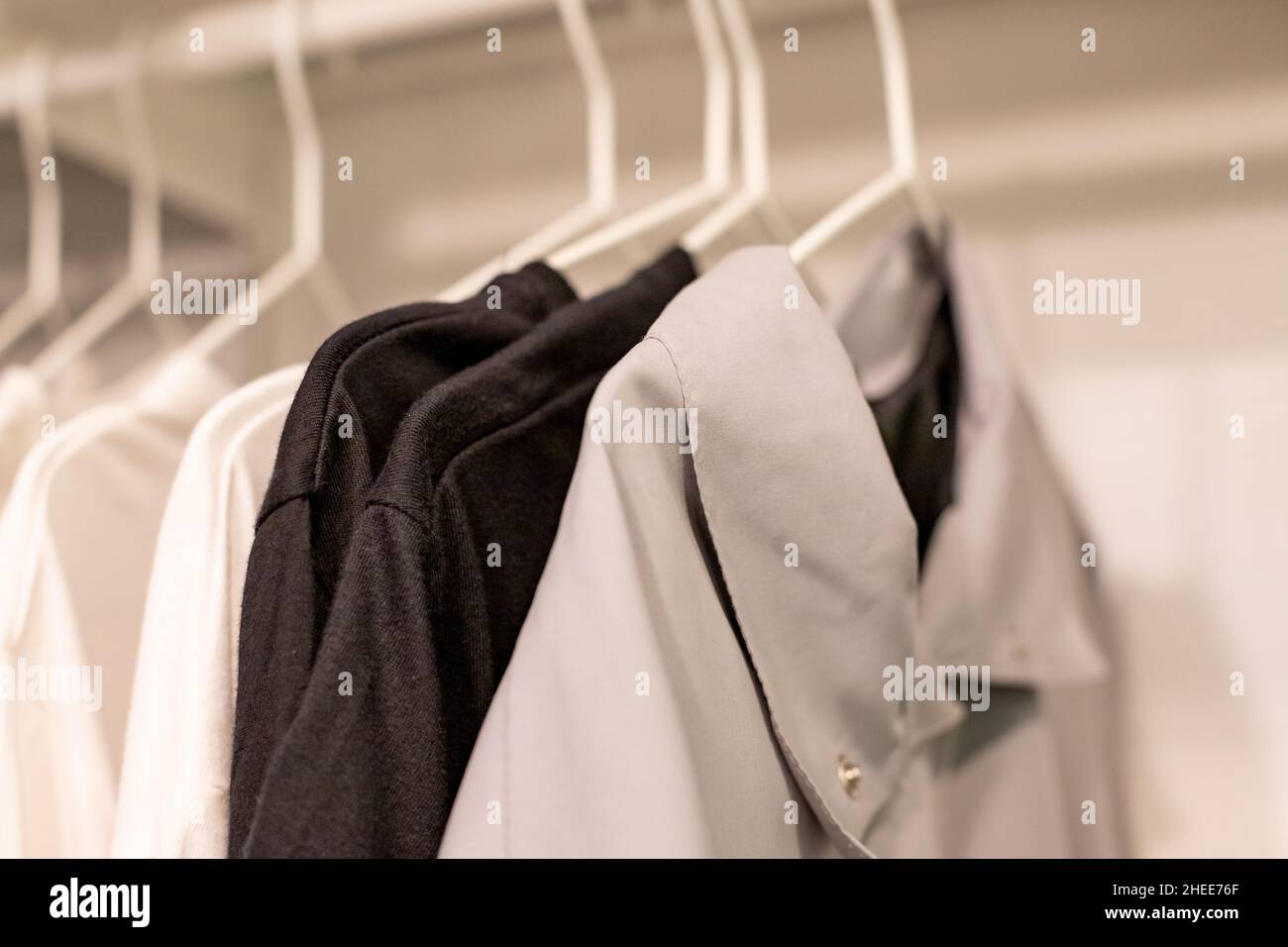 Clothes on a rail in a wardrobe. Seasonal capsule for easy dressing, order in things, cleaning out Stock Photo