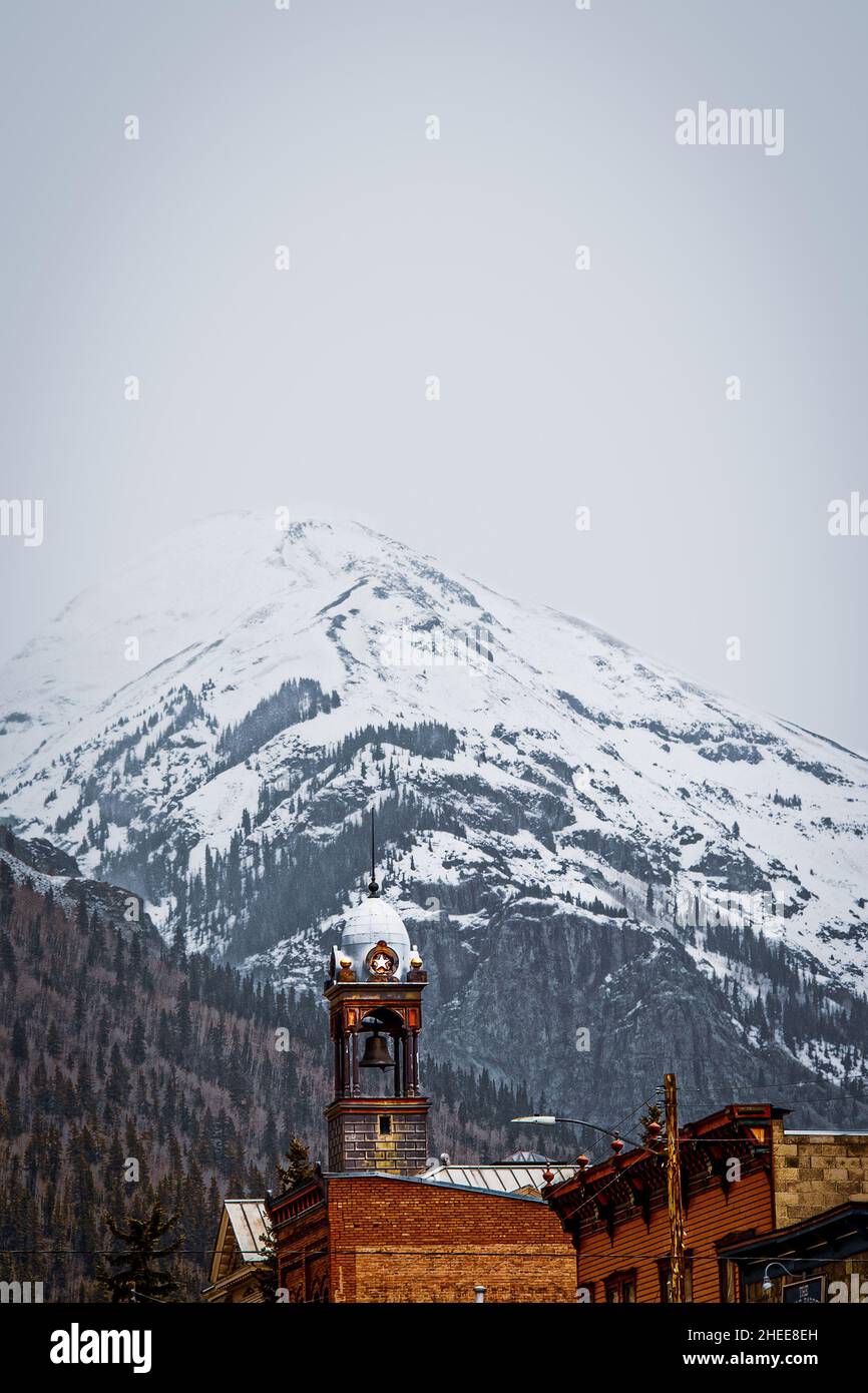 Tower of historic old City Hall in Silverton Colorado in the San Juan Mountains of Colorado CA USA with snowy mountains in the background on overcast Stock Photo