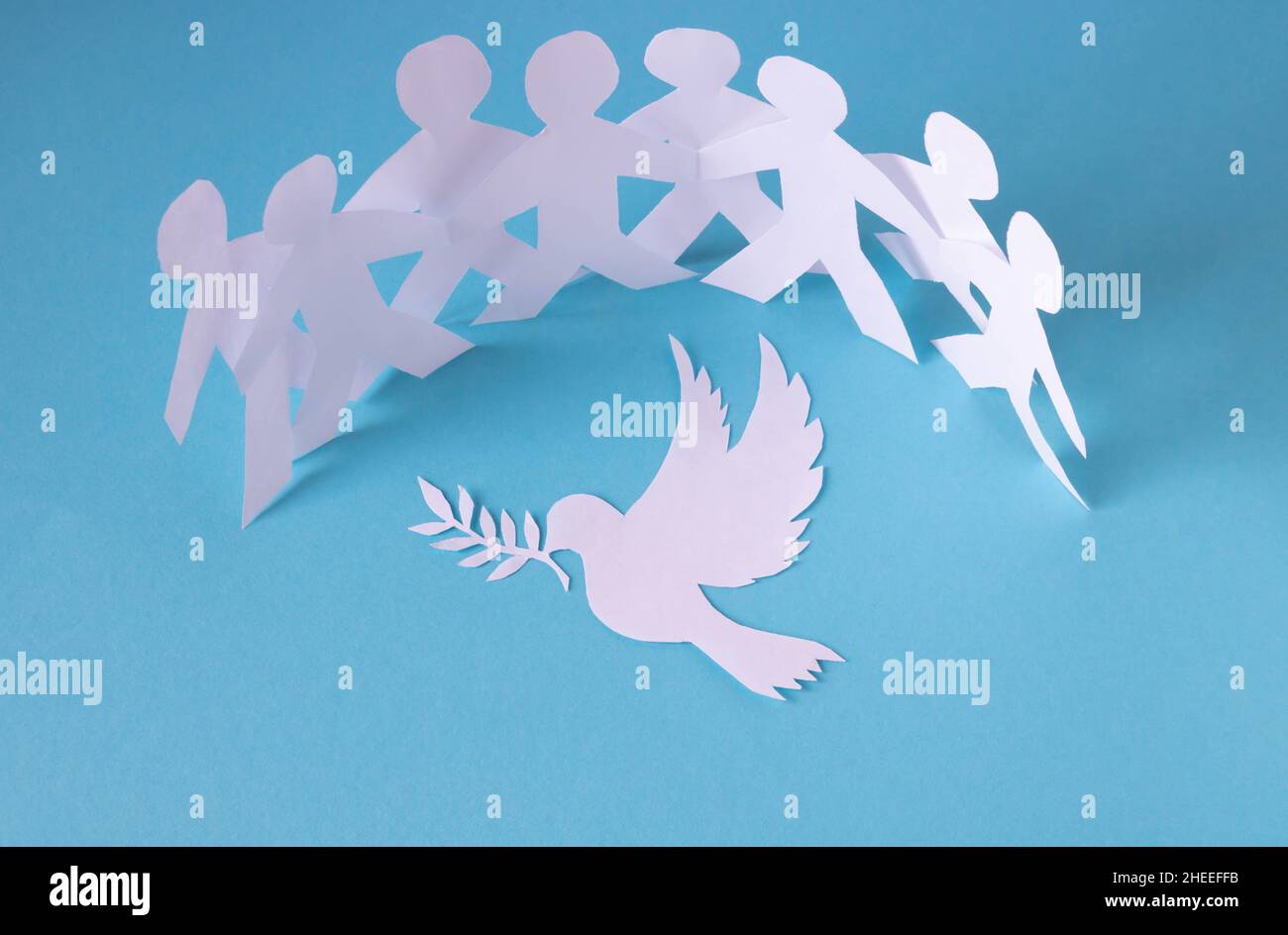 People cut out of paper on a blue background protect the dove of peace.The concept of the World Peace Day. Stock Photo