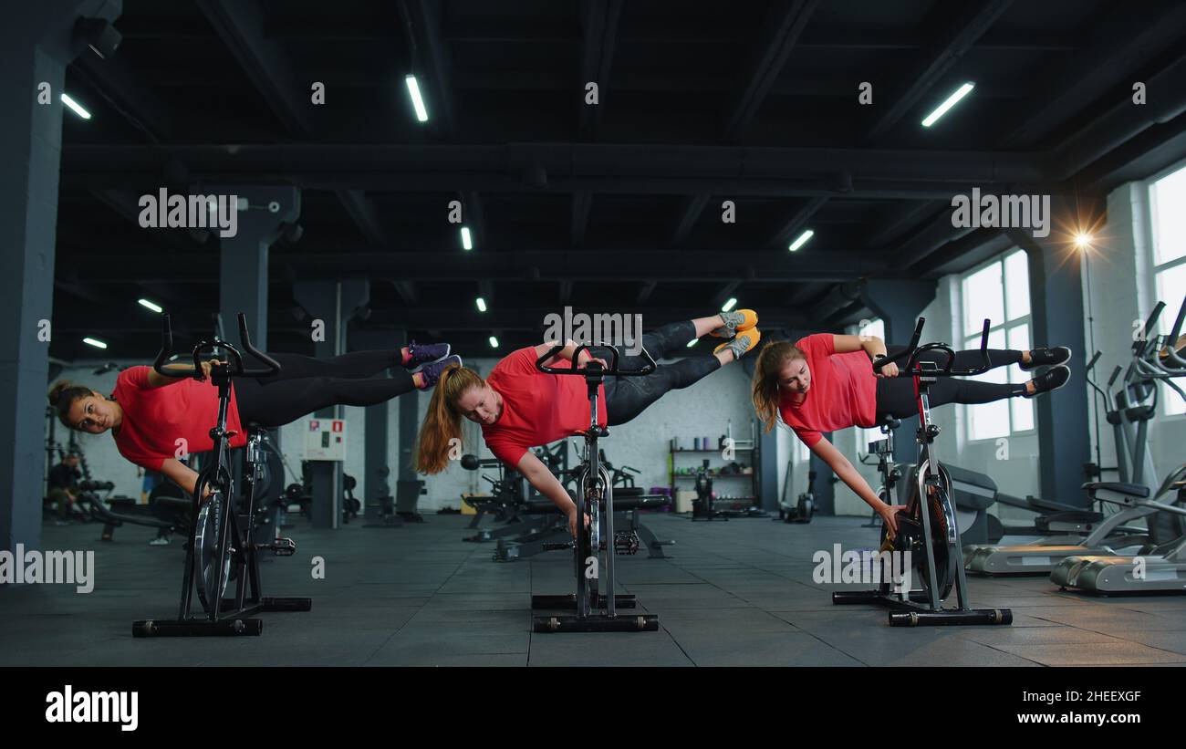 Athletic women group training tricks on spinning stationary bike