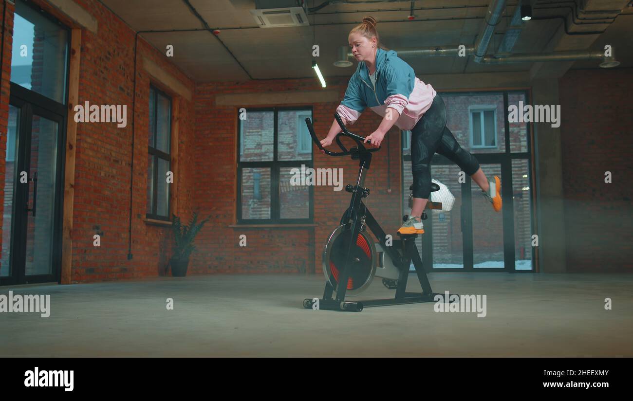 Athletic woman riding on spinning stationary bike training routine in