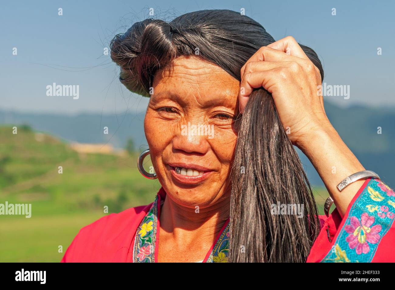 Smiling long haired woman portrait of Yao ethnic group by the Longsheng Ping An rice terraces, Guangxi province, China. Stock Photo