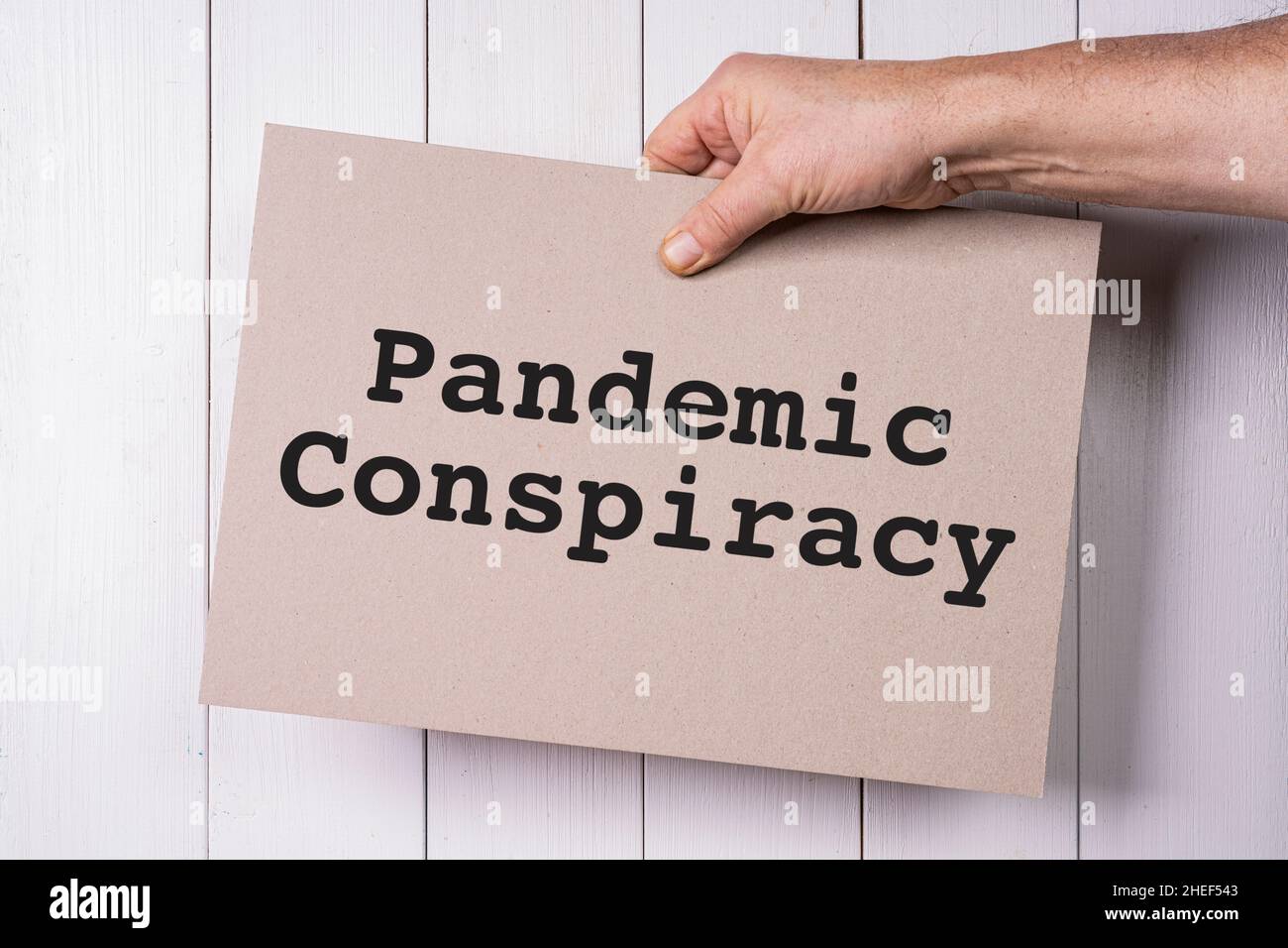 a sign with the words Pandemic conspiracy held in the hand Stock Photo