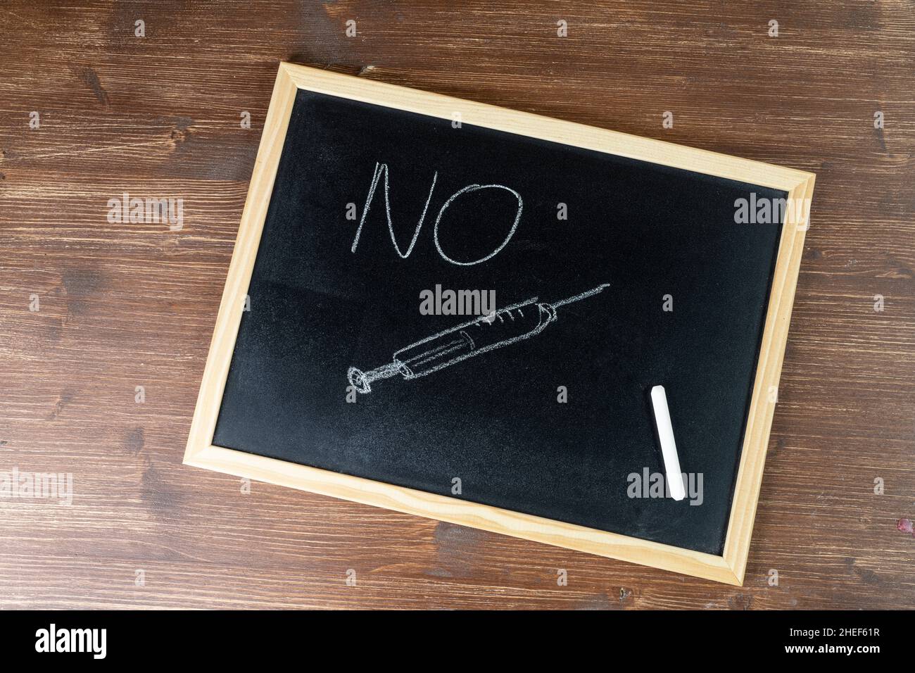 A syringe and the word No written with chalk on a blackboard Stock Photo