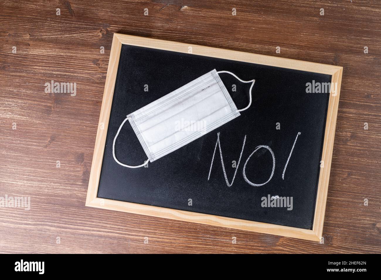 A mask and the word No written with chalk on a blackboard Stock Photo