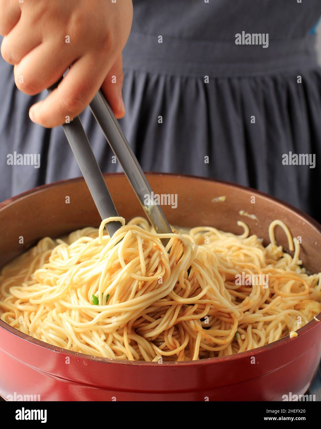 Female Hand Roll Asian Egg Noodle or Spaghetti on Red Pan, with Tongs ...