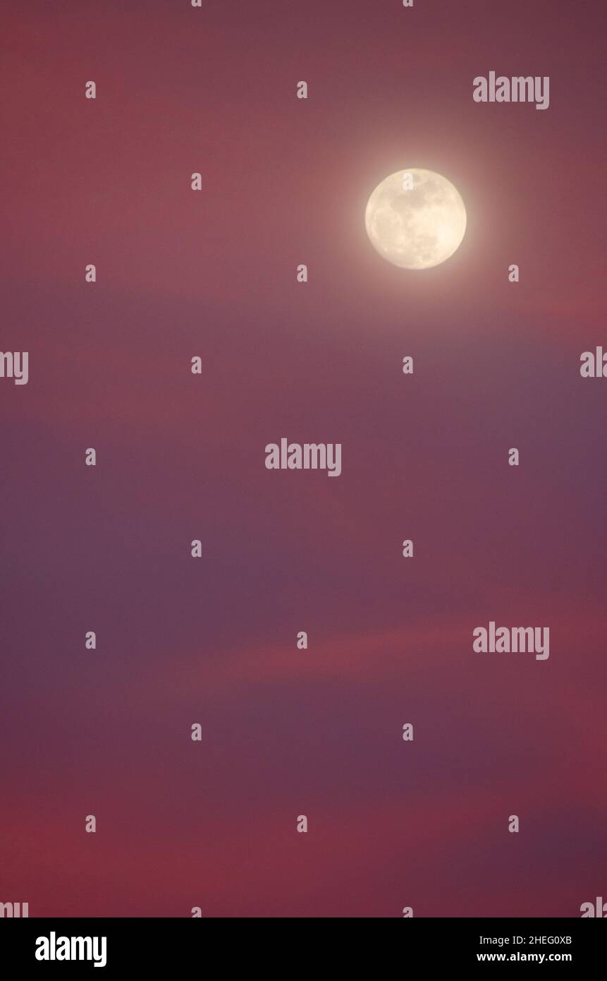 Full moon and colorful clouds at sunset Stock Photo