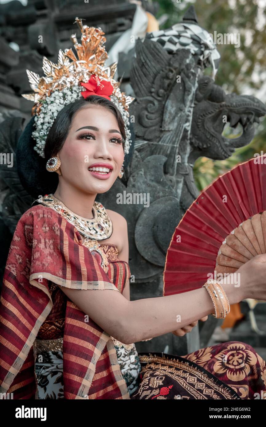 Portrait Bali girl with a traditional dress standing with folding fan ...
