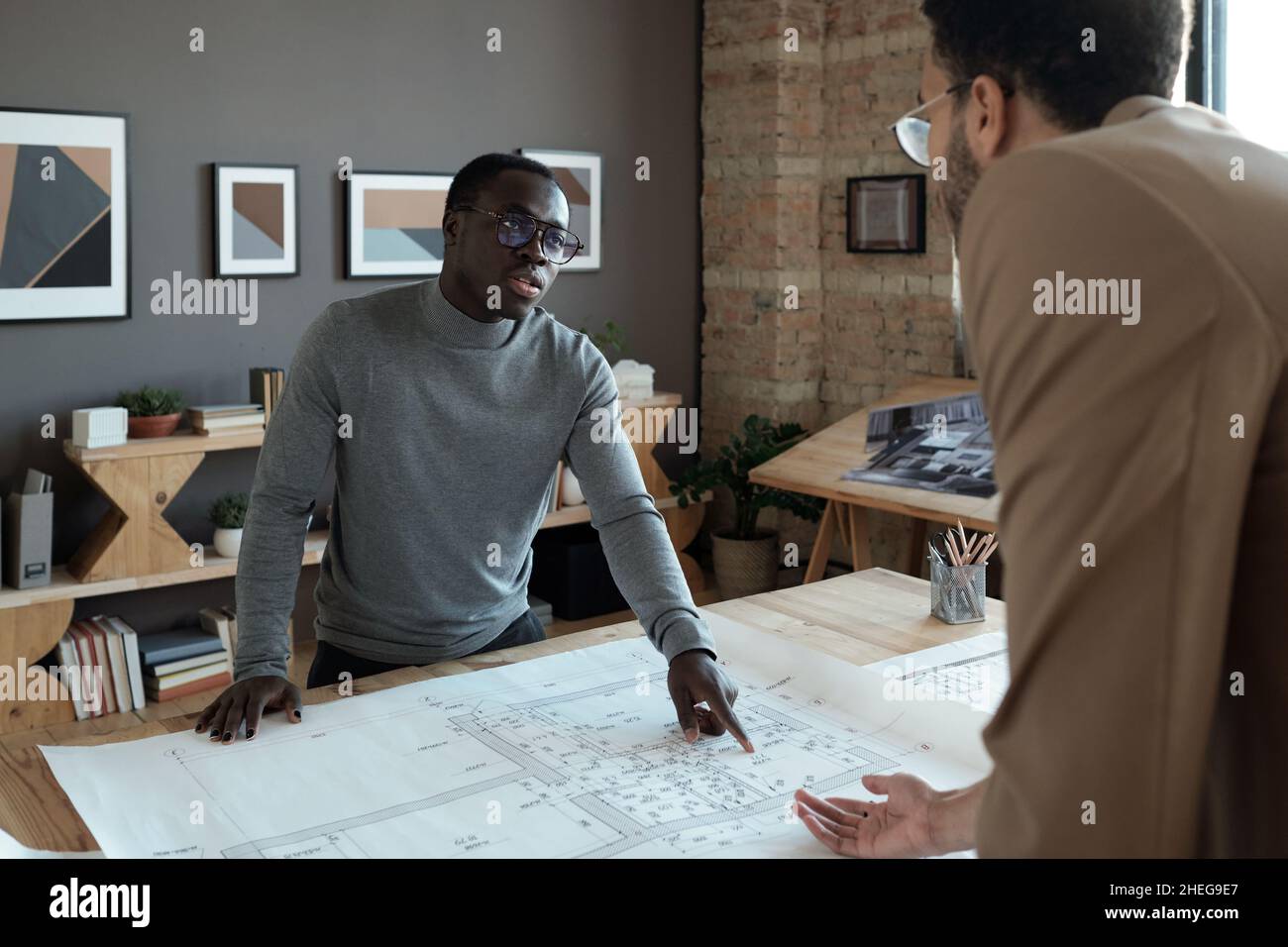 Young contemporary African architect explaining details of sketch to ...