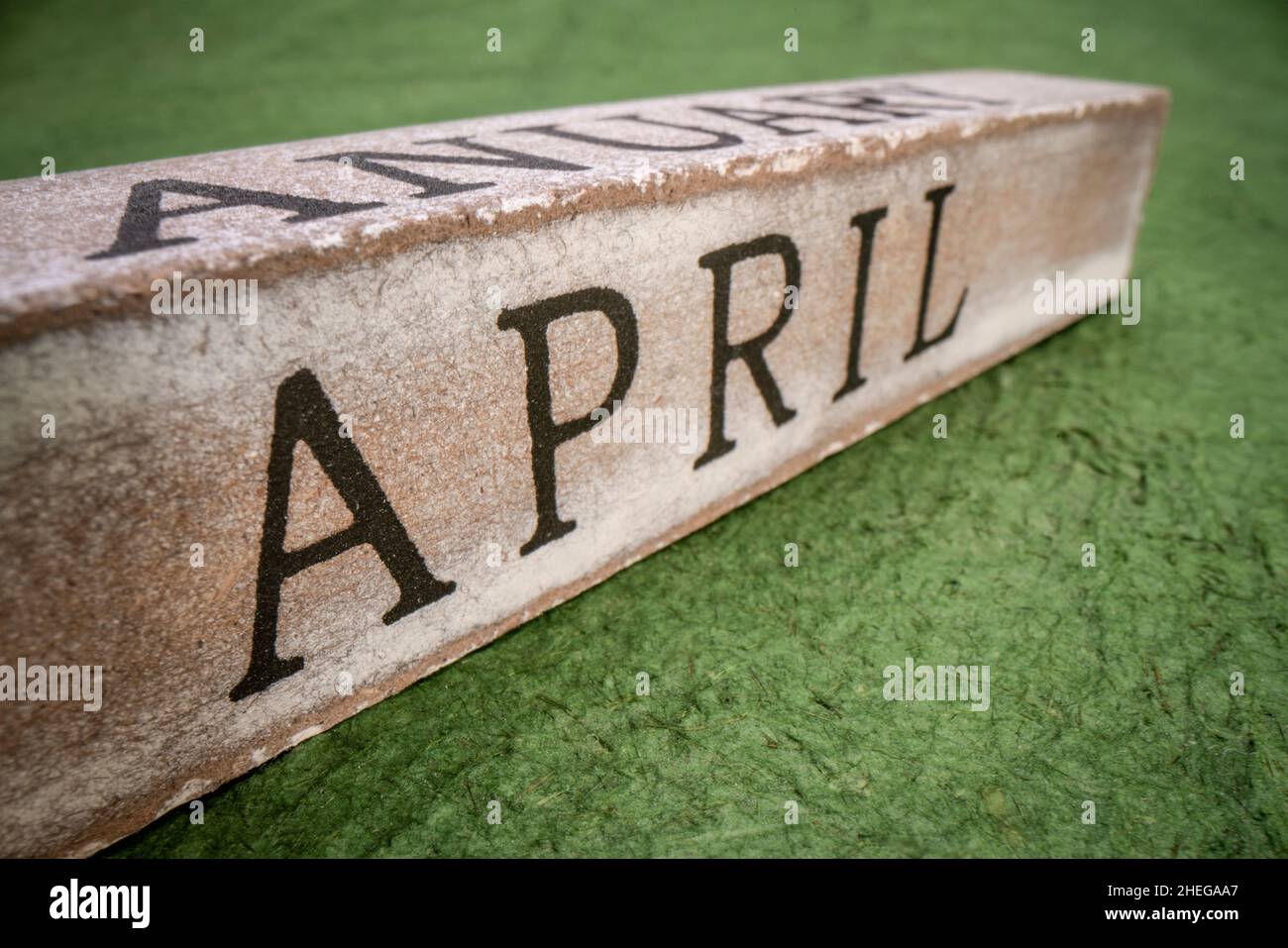 April text on grunge wooden block against handmade textured paper ...