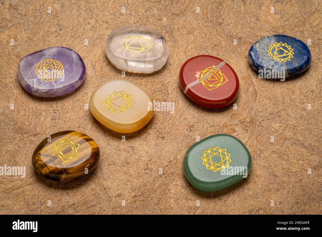 seven chakra stones with symbol engraving on a textured, handmade, bark paper, reiki healing concept Stock Photo