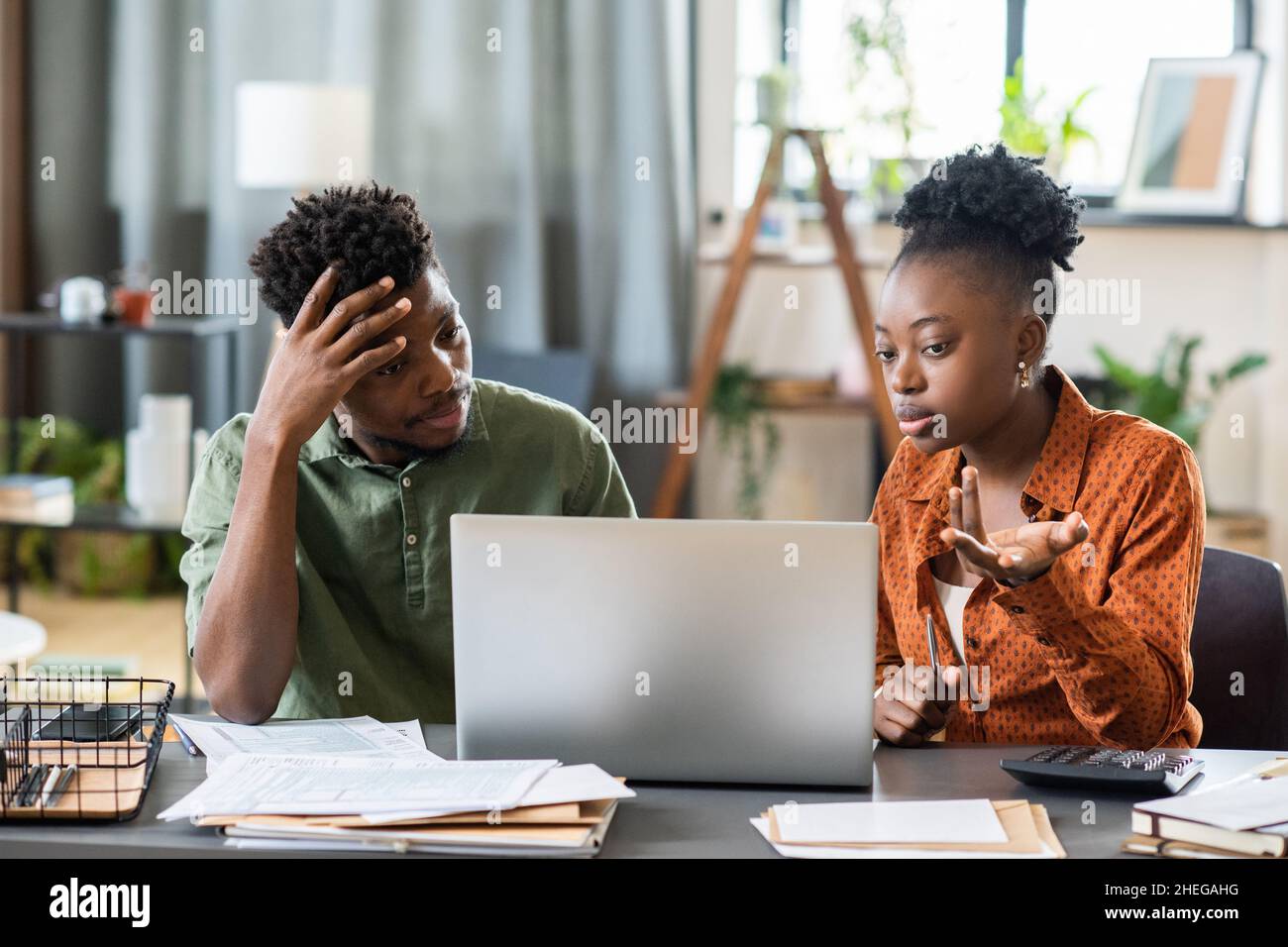 Young African woman and man looking at laptop screen while female explaining online data to male colleague Stock Photo