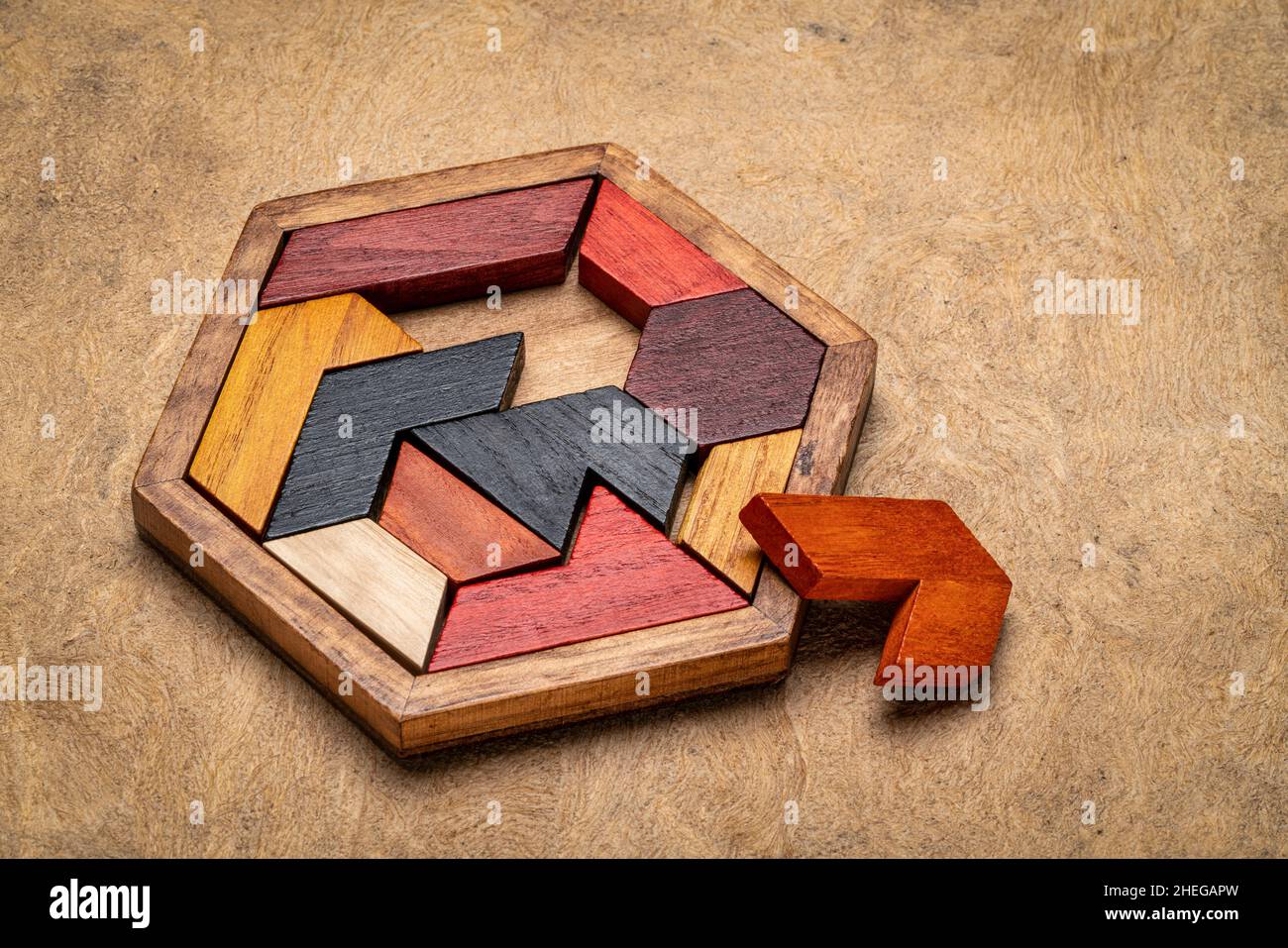 wooden hexagon tangram puzzle against textured handmade bark paper, brain teaser and fun game with multiple ways to solve Stock Photo