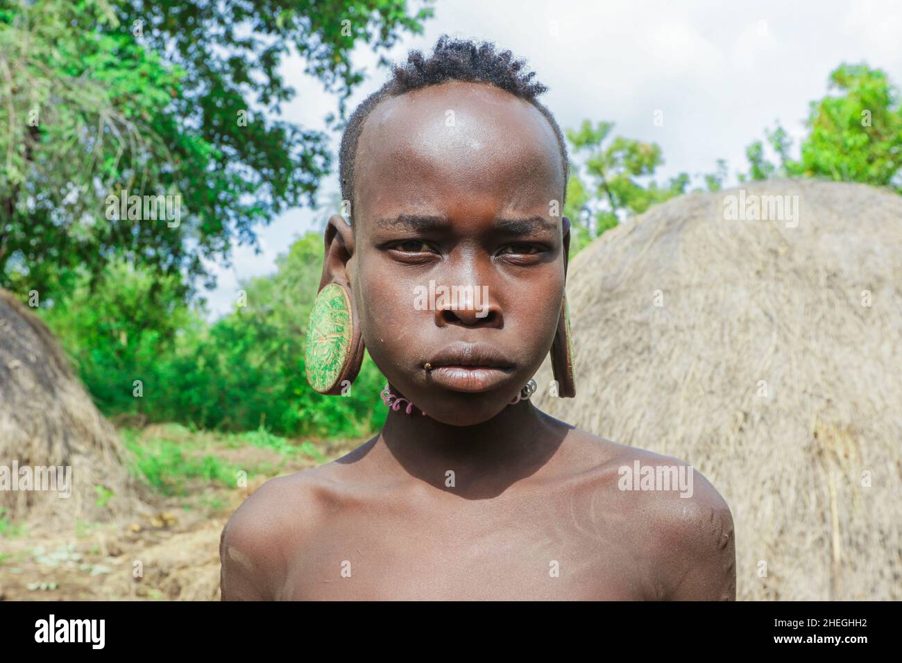 Omo River Valley, Ethiopia - November 29, 2020: Portrait of African Teenager with a big traditional wooden earrings in the local Mursi tribe village Stock Photo
