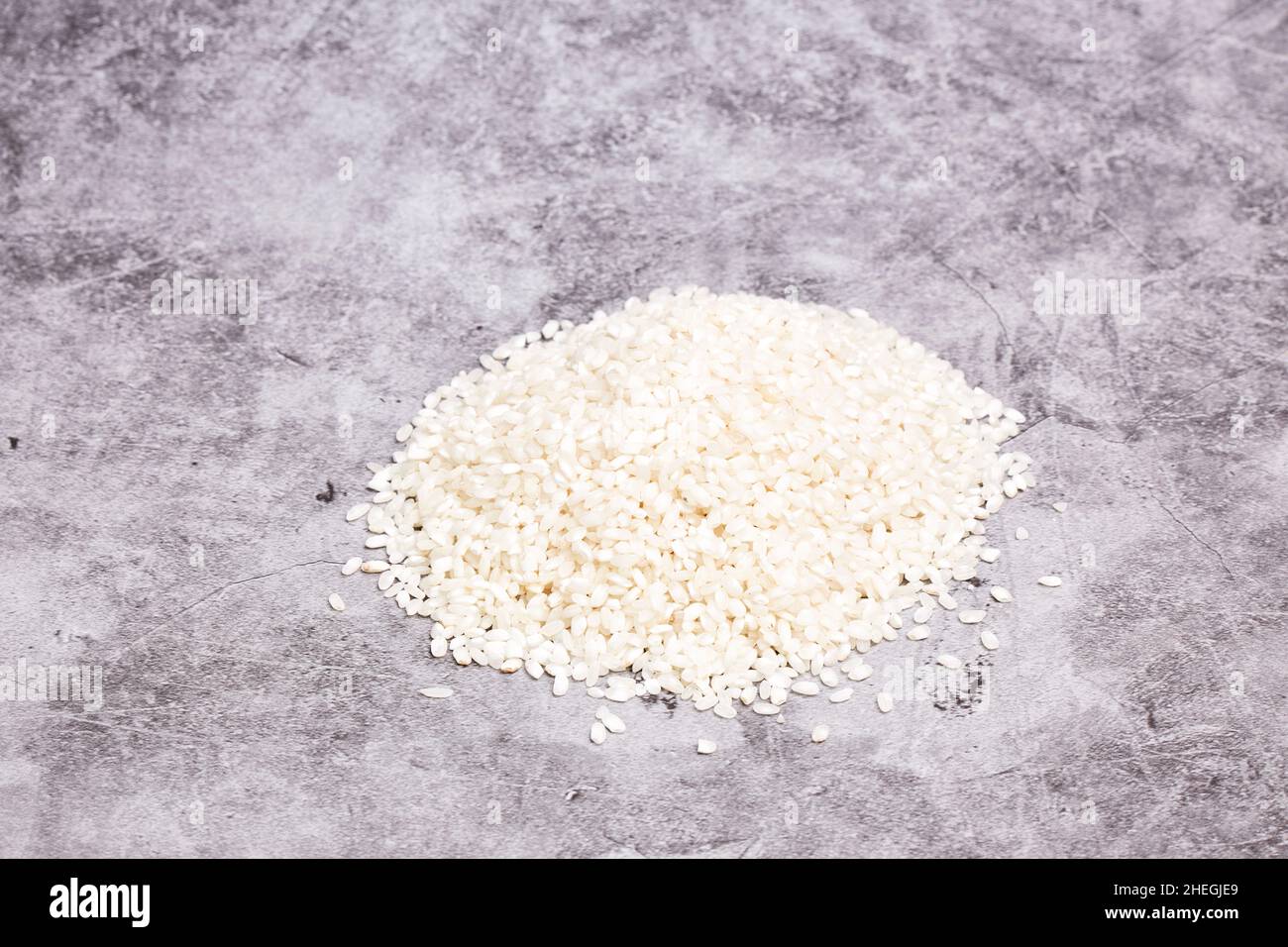 Pile of white rice grains on a gray stone background. Oriental and healthy food Stock Photo