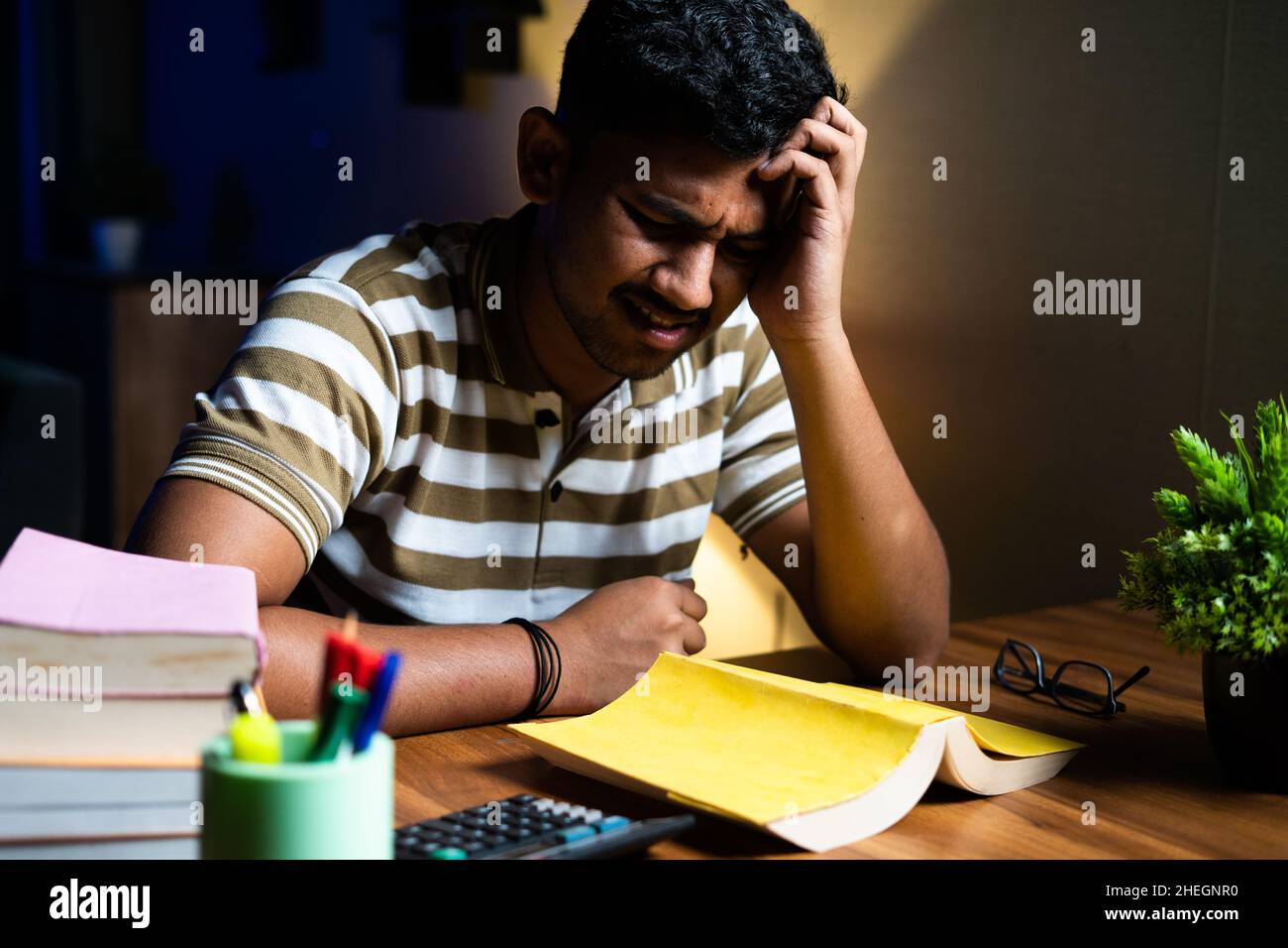 Young student suffering understanding from book while reading or studying for examination - concept of confusion, weak phonemic awareness and Stock Photo