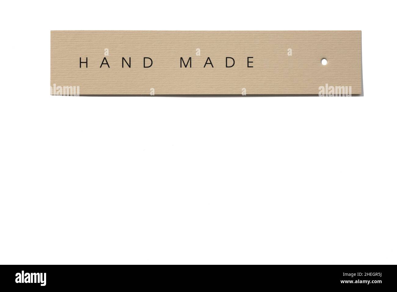 Clothes tag of rectangle shape positioned horizontally on white background with small hole in right side with inscription on it indicating that Stock Photo