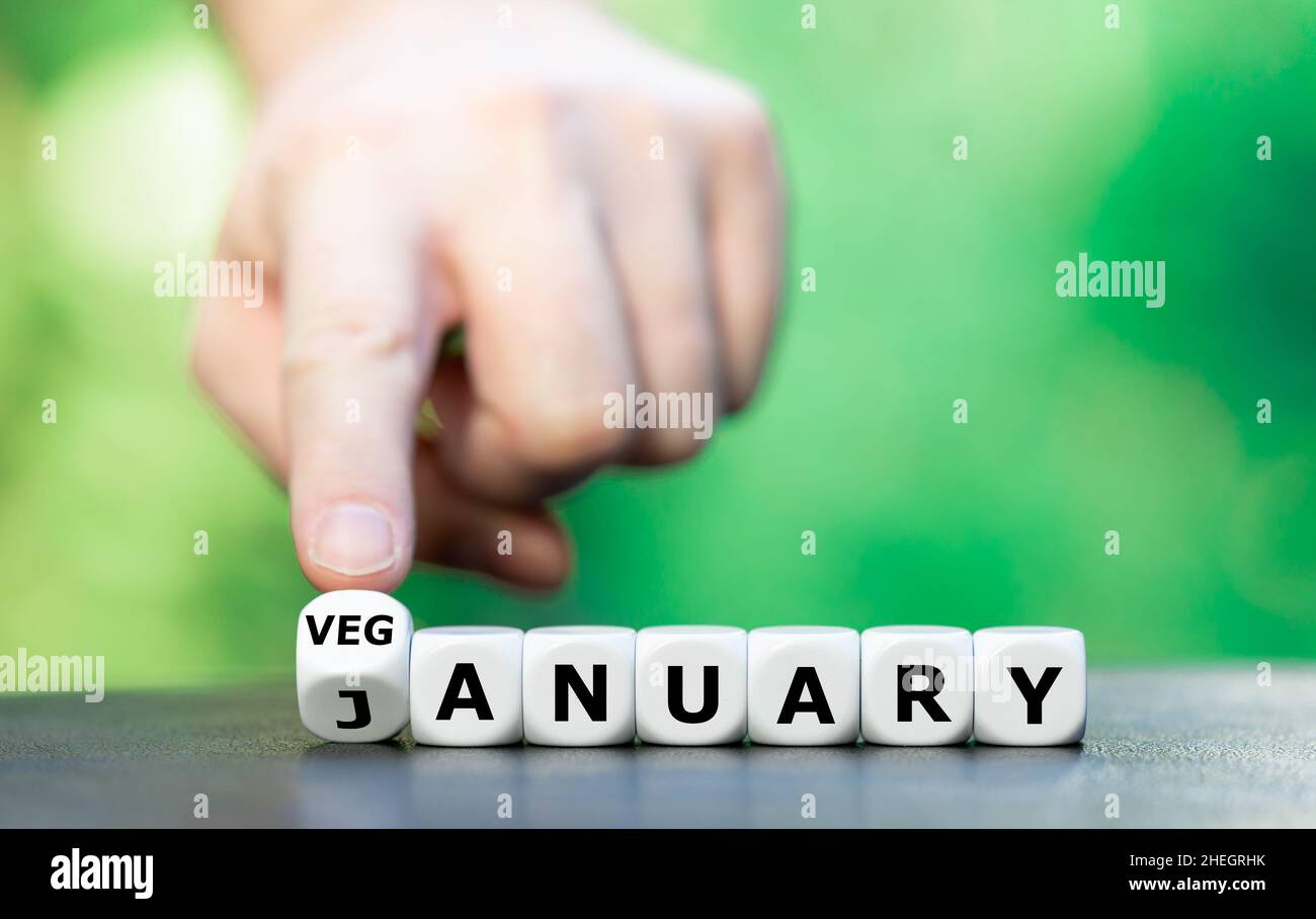 Symbol for the Veganuary, a vegan lifestyle for the month of January. Hand turns dice and changes the word January to Veganuary. Stock Photo