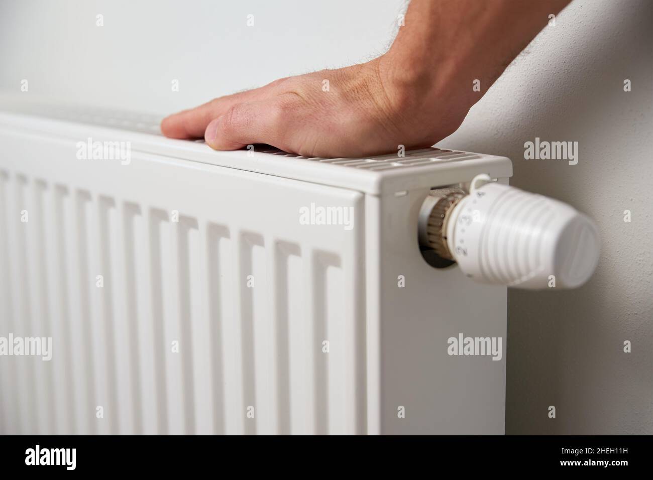 Hand adjusting temperature on heating radiator thermostat, Turning heat