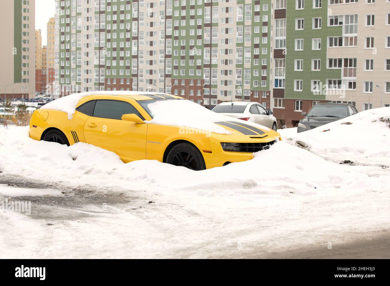 Yellow Chevrolet Camaro with black stripes standing at car parking in winter. Omsk, Russia, 29.02.2020 Stock Photo