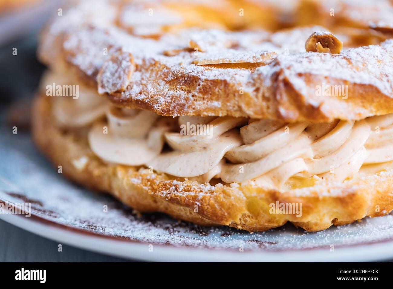Traditional french Dessert called Paris Brest on a grey background with powder sugar and almond