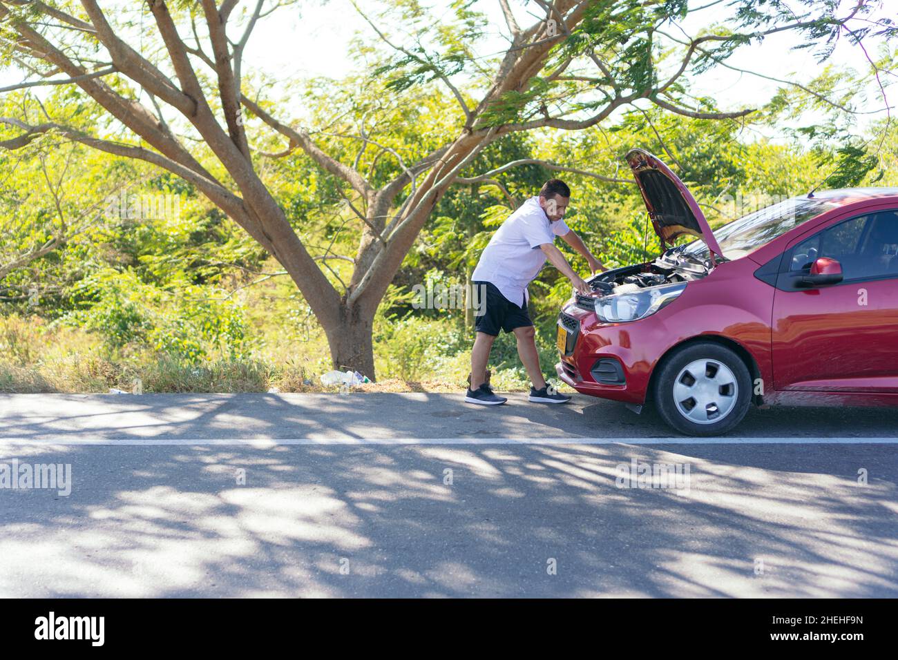 Man on the side of the road with a broken down car Stock Photo - Alamy