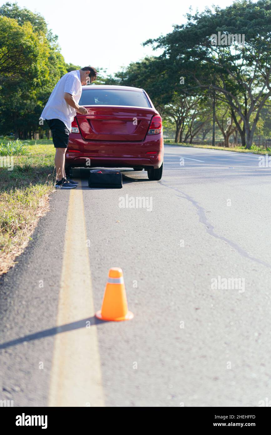 Man on the side of the road with a broken down car Stock Photo - Alamy