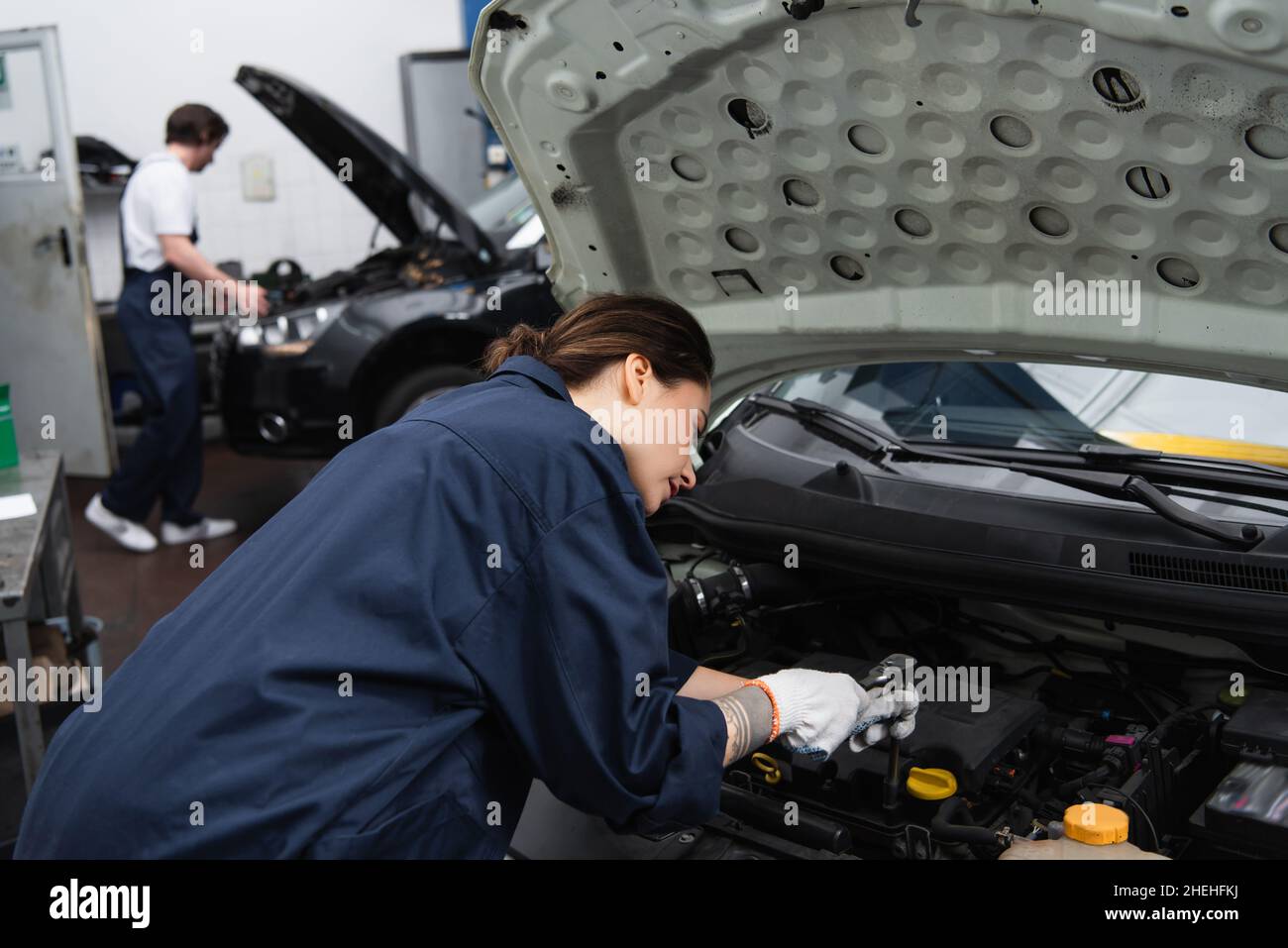 Forewoman working with car engine in garage Stock Photo