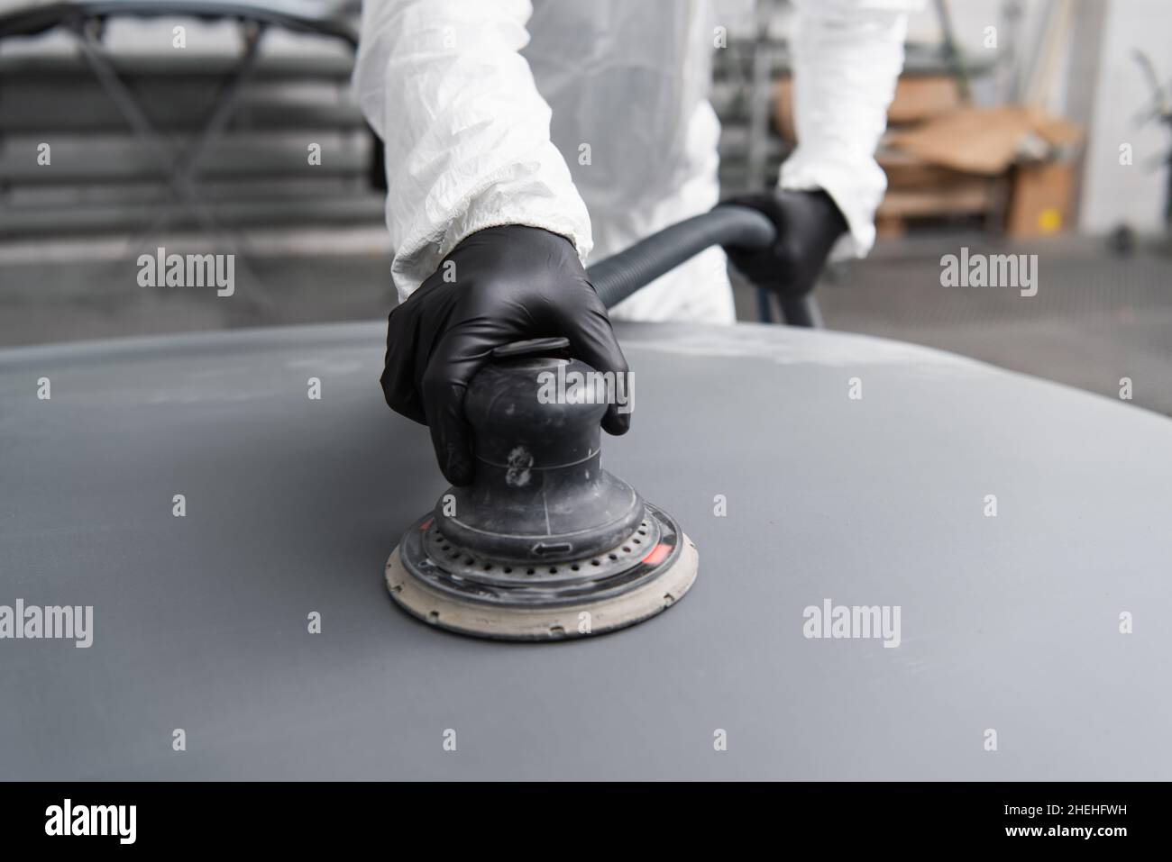 Cropped view of workman in gloves and hazmat suit polishing car in garage Stock Photo