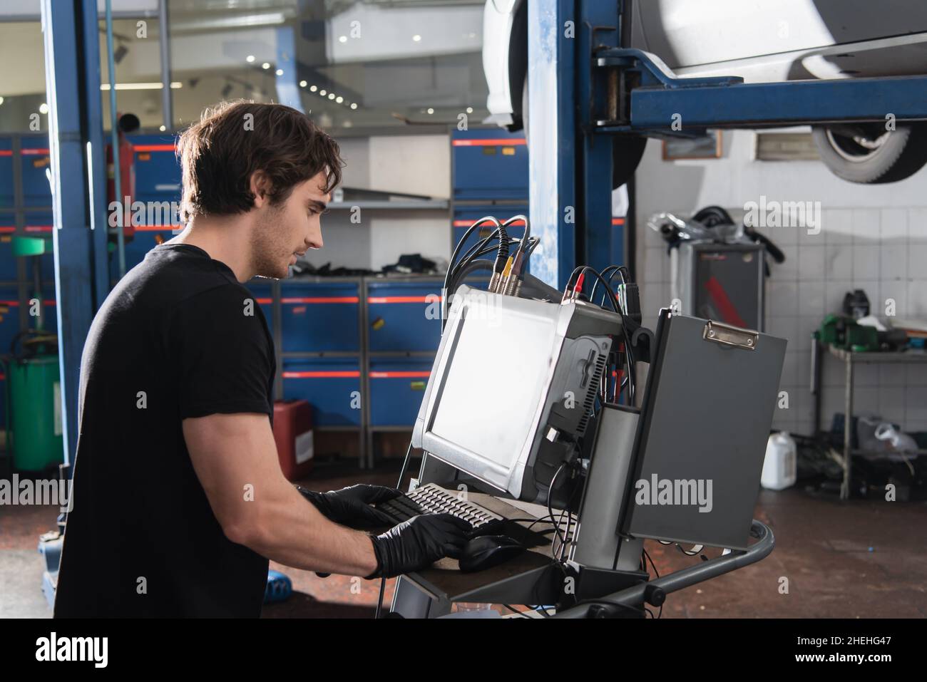 Side view of mechanic in gloves using computer in car service Stock ...