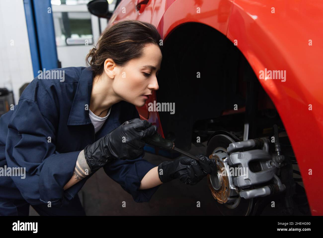 Side view of mechanic using screwdriver on car wheel in service Stock