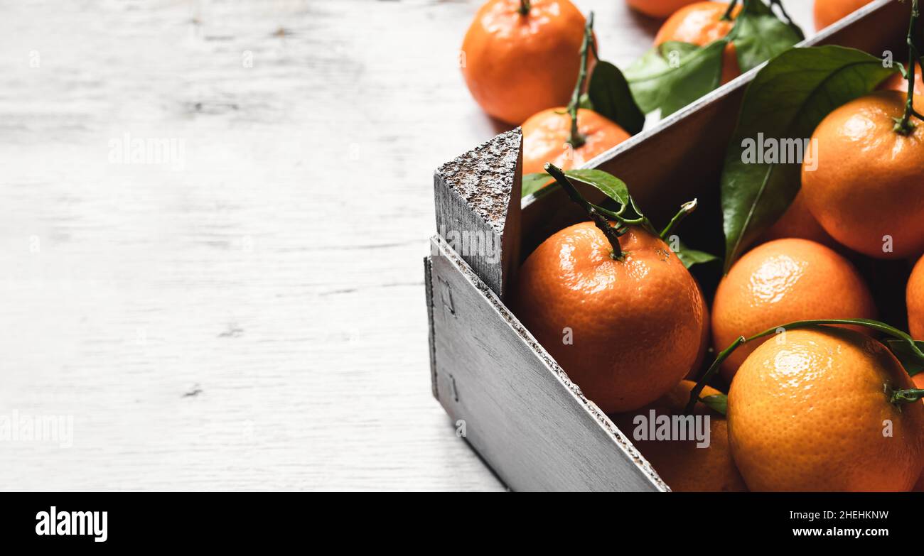 A box with fresh tangerines on on a white wooden table with copy space Stock Photo