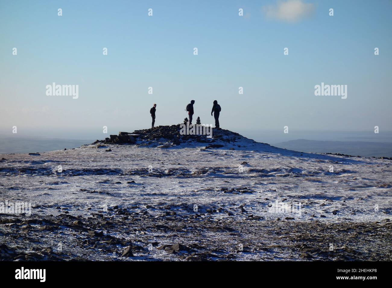 Three People Standing on the Summit Cairn of Ingleborough (1 of the Yorkshire 3 Peaks) Yorkshire Dales National Park, England. Stock Photo