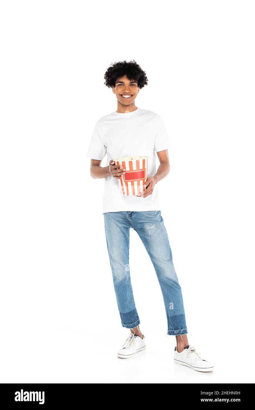 full length view of happy african american man in jeans holding bucket of  popcorn on white Stock Photo - Alamy