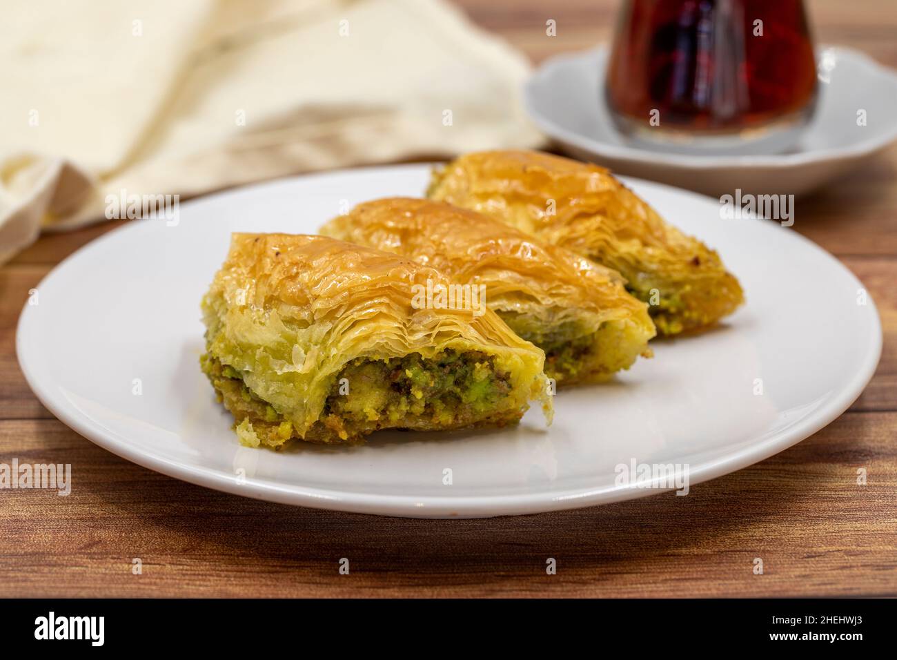 Pistachio baklava (Sobiyet) on wooden background. Traditional Turkish cuisine delicacies. Close-up. Stock Photo