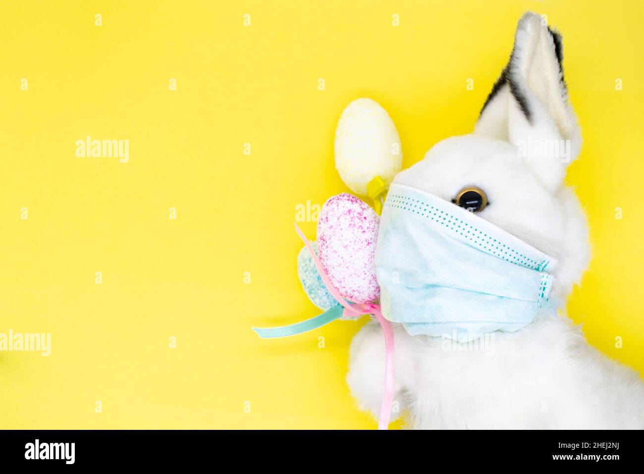 Easter Bunny in a facial medical mask with a bouquet of colorful eggs ...