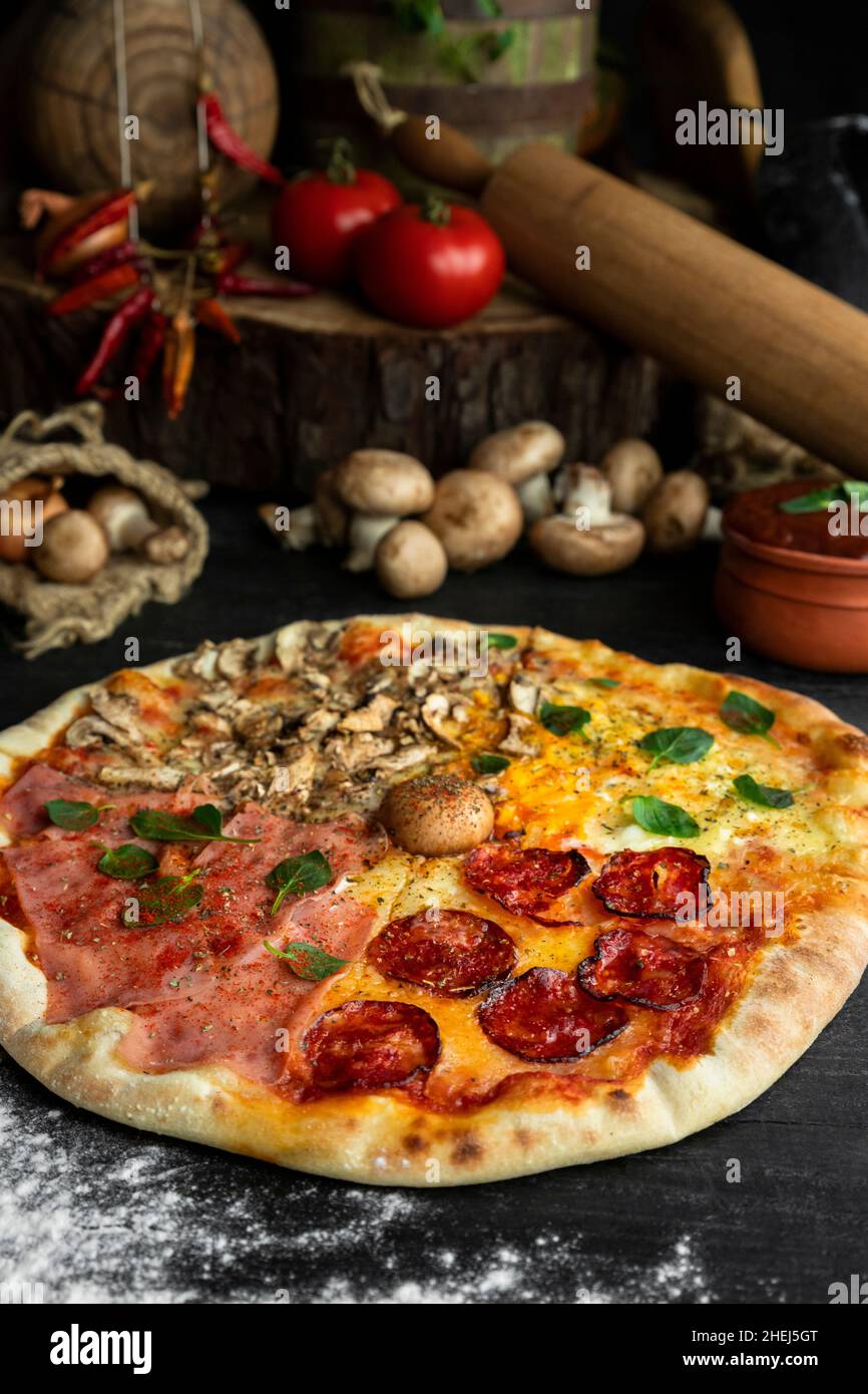 Italian Pizza Four Seasons (Pizza Quattro Stagioni) with different  ingredients on the wooden table in the kitchen. Italian homemade recipes  Stock Photo - Alamy